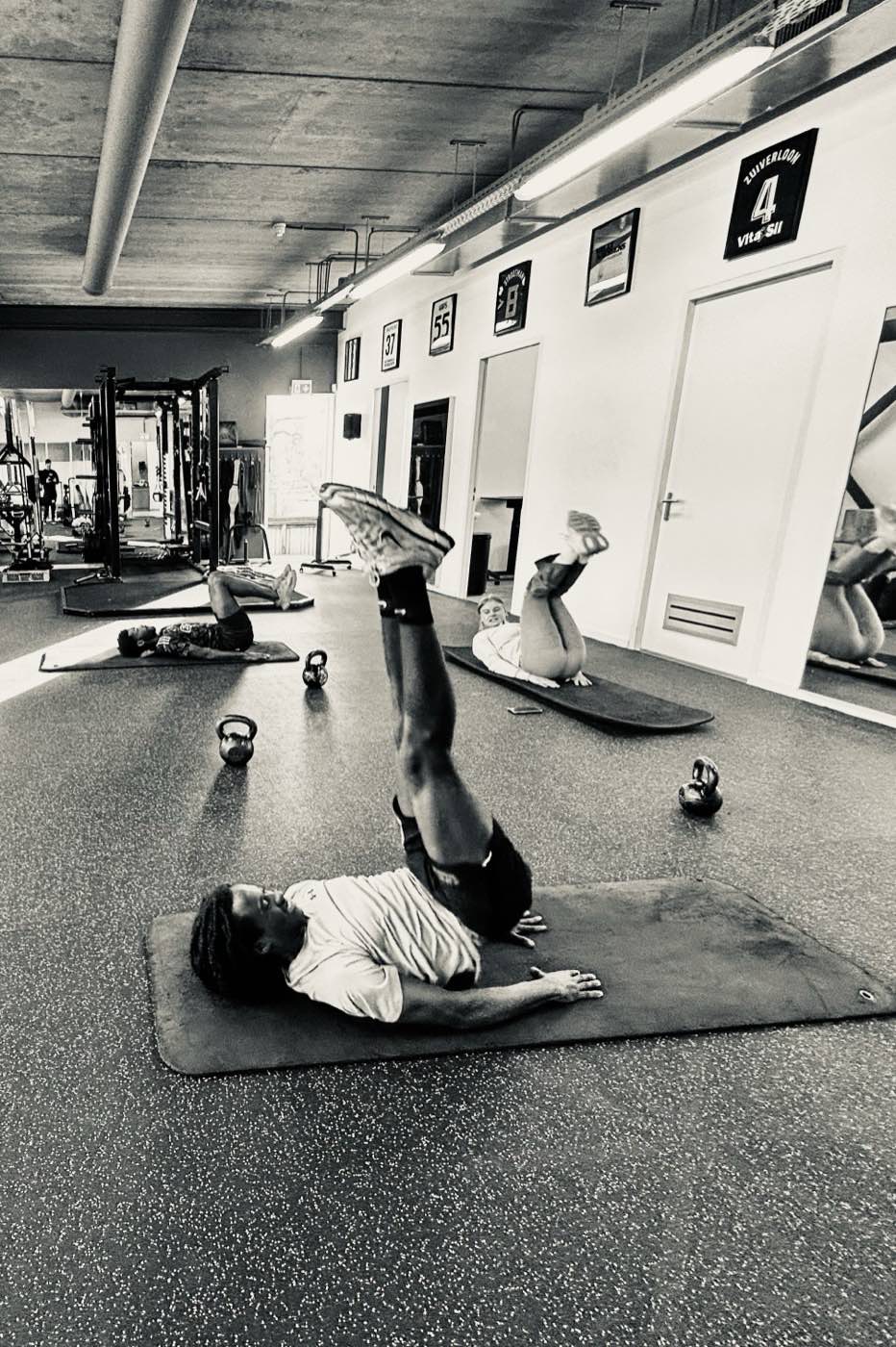 Sporters doen core-oefeningen op matten in de trainingsruimte van PhysioLab Amsterdam